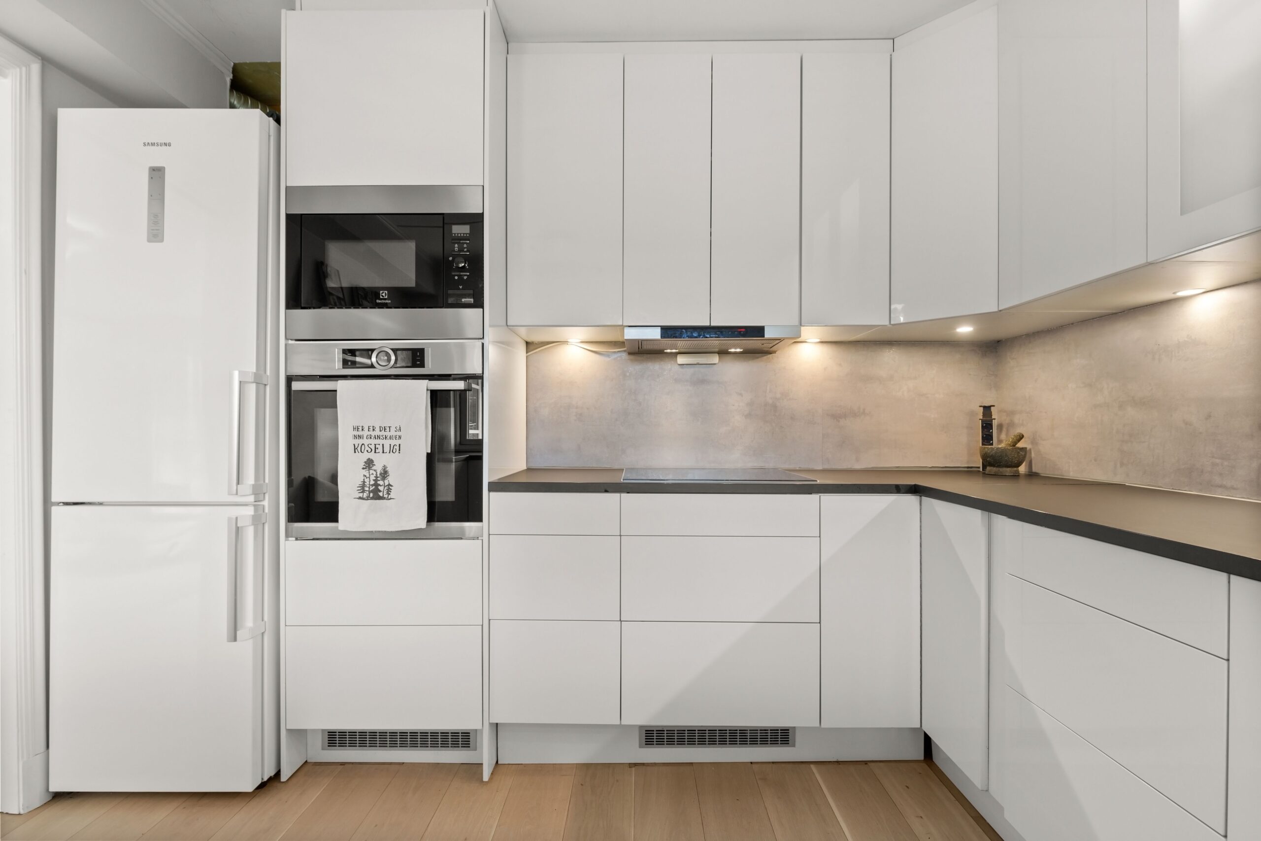 Sleek modern kitchen featuring white cabinetry, built-in appliances, and minimalist design.